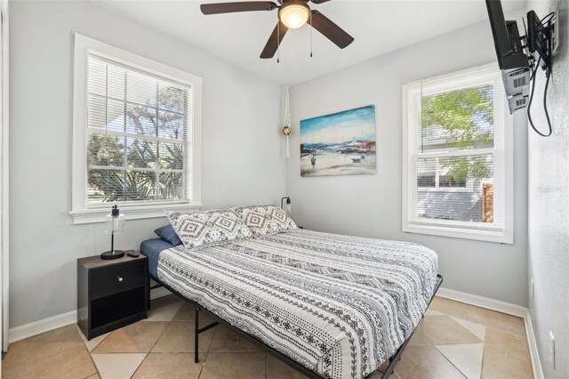 tiled bedroom featuring multiple windows and ceiling fan