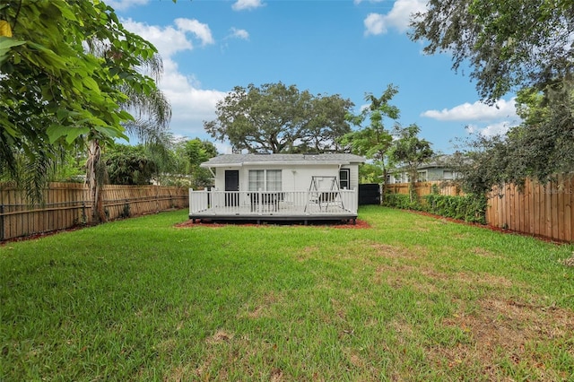 rear view of property featuring a wooden deck and a lawn