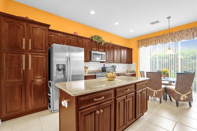 kitchen with a kitchen island, light stone counters, hanging light fixtures, appliances with stainless steel finishes, and light tile patterned floors