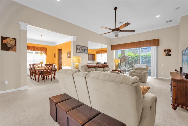 carpeted living room featuring ceiling fan with notable chandelier, plenty of natural light, and ornamental molding