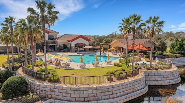 community pool featuring fence, a patio area, and a lawn