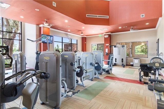 gym featuring ornamental molding, ceiling fan, and a towering ceiling