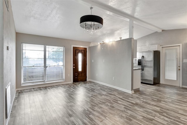 foyer featuring light wood-type flooring, vaulted ceiling with beams, and a notable chandelier