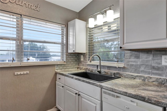 kitchen with decorative backsplash, dishwasher, white cabinetry, and sink