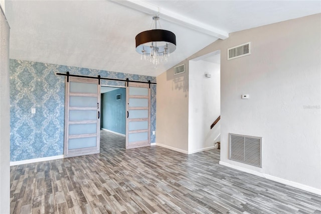 spare room featuring an inviting chandelier, hardwood / wood-style flooring, lofted ceiling with beams, and a barn door