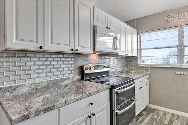 kitchen with stainless steel range with electric cooktop, white cabinets, and backsplash