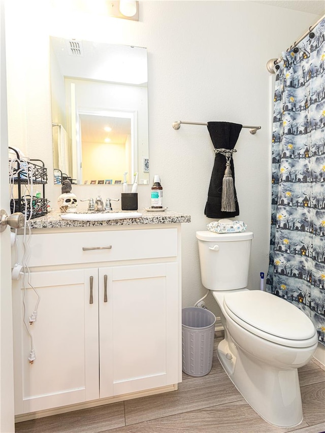 bathroom featuring wood-type flooring, curtained shower, vanity, and toilet