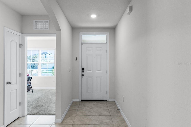 doorway featuring light tile patterned floors and a textured ceiling