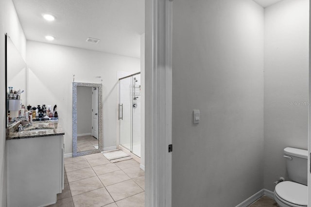 bathroom with tile patterned floors, vanity, toilet, and walk in shower