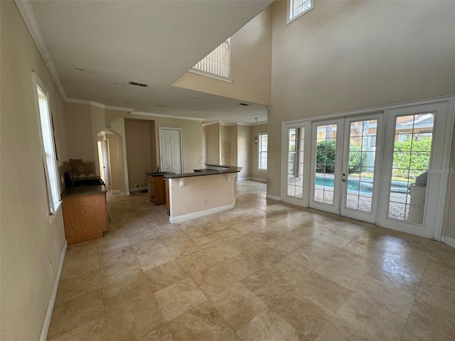 unfurnished living room with a high ceiling, french doors, and crown molding