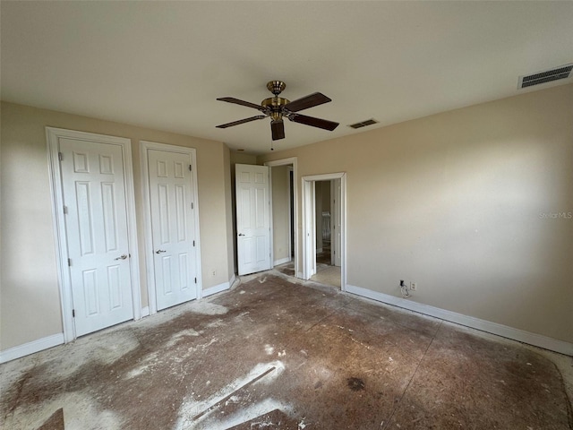 unfurnished bedroom featuring ceiling fan and two closets