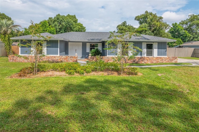 ranch-style house with roof with shingles, a front yard, fence, and brick siding