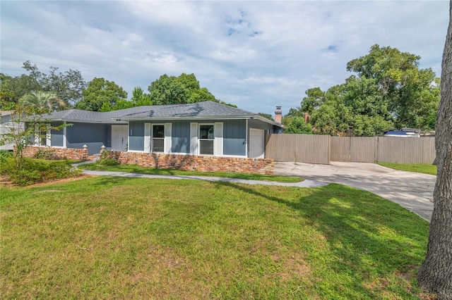 view of front facade featuring driveway, a front lawn, fence, and brick siding