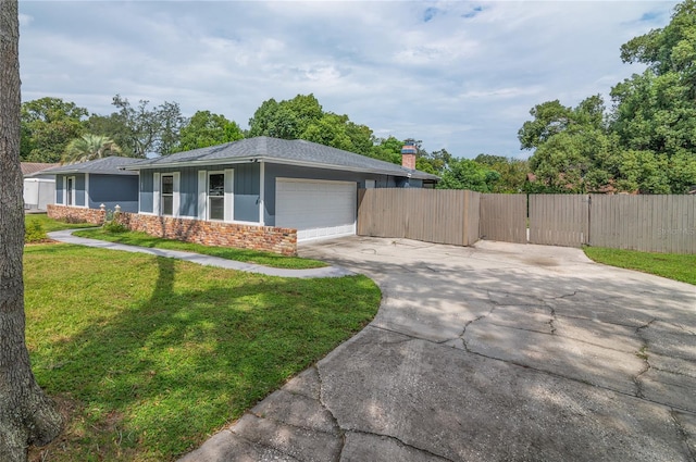 view of front facade with a front yard, concrete driveway, fence, and an attached garage