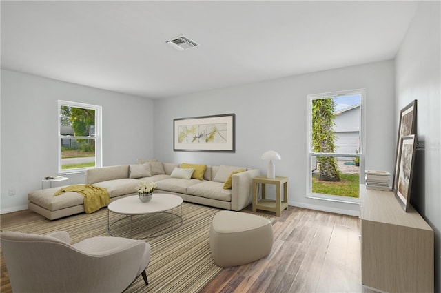 living room featuring visible vents, baseboards, and wood finished floors