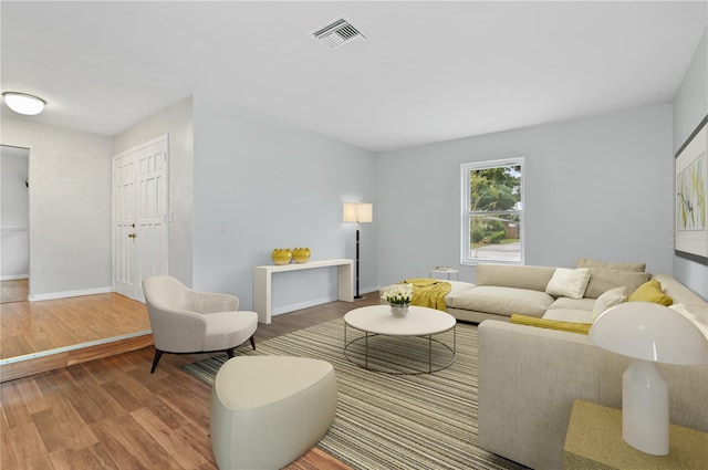 living room with visible vents, baseboards, and wood finished floors