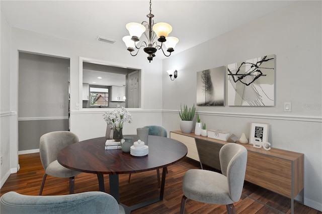 dining space with a chandelier, wood finished floors, visible vents, and baseboards