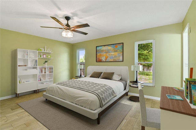 bedroom featuring ceiling fan, light wood finished floors, and baseboards