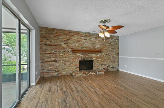 unfurnished living room featuring a fireplace, a textured ceiling, baseboards, and wood finished floors