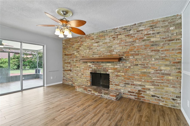 unfurnished living room featuring a fireplace, ceiling fan, a textured ceiling, wood finished floors, and baseboards