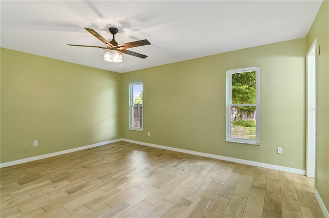 unfurnished room featuring ceiling fan, light wood-style floors, baseboards, and a healthy amount of sunlight