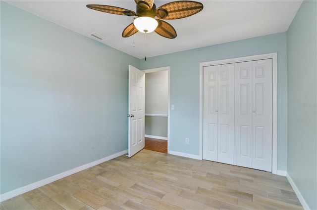 unfurnished bedroom featuring ceiling fan, visible vents, baseboards, a closet, and light wood finished floors