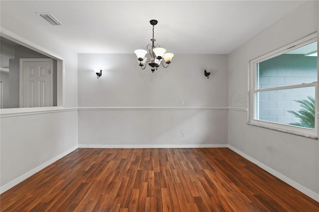 spare room featuring baseboards, wood finished floors, visible vents, and a notable chandelier