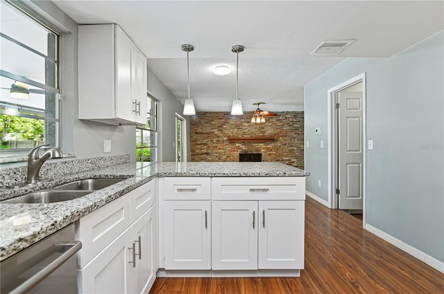 kitchen featuring a peninsula, a sink, visible vents, stainless steel dishwasher, and light stone countertops