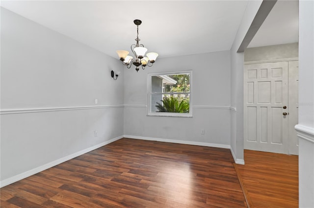 unfurnished dining area with an inviting chandelier, baseboards, and wood finished floors