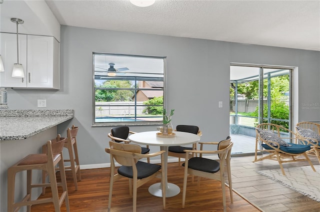 dining room featuring dark wood-type flooring, a textured ceiling, and baseboards