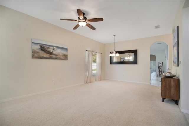 carpeted spare room featuring ceiling fan with notable chandelier