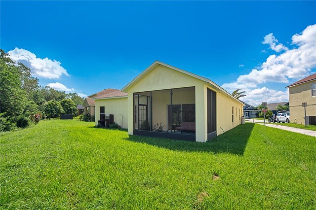 1033 Hacienda Cir, Kissimmee, FL 34741 - back of property with a sunroom, stucco siding, and a lawn