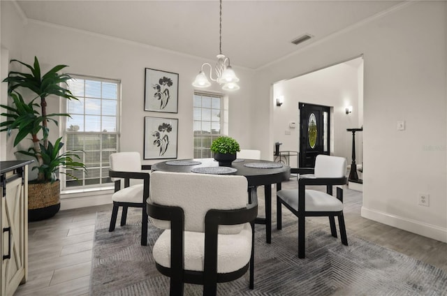 dining space featuring hardwood / wood-style floors, a chandelier, and ornamental molding