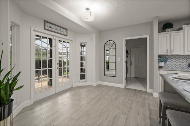 interior space featuring french doors, a textured ceiling, and light hardwood / wood-style flooring