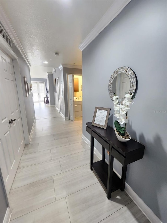 hall with washing machine and clothes dryer, crown molding, and a textured ceiling