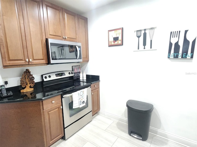 kitchen featuring dark stone countertops, light tile patterned floors, and appliances with stainless steel finishes