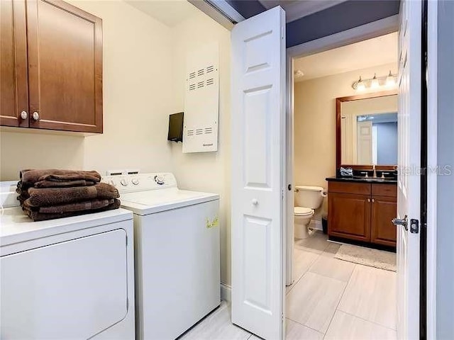 laundry area with cabinets, light tile patterned floors, washer and clothes dryer, and sink