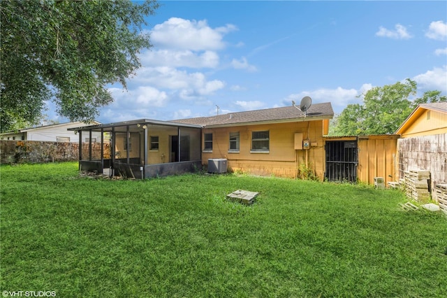 back of property featuring a sunroom, cooling unit, and a lawn