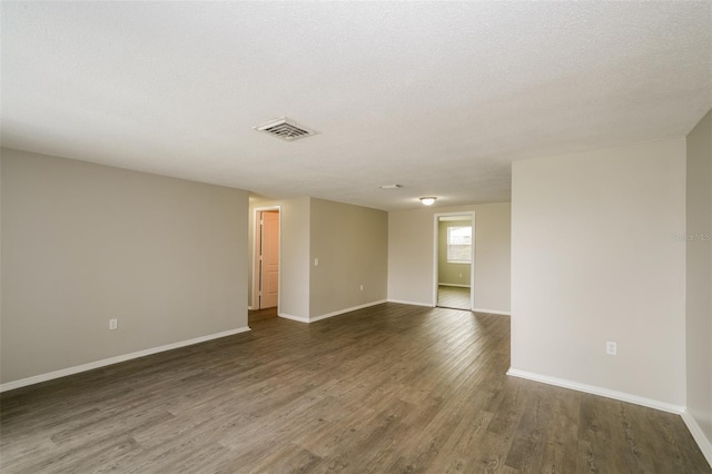 unfurnished room featuring a textured ceiling and dark hardwood / wood-style floors