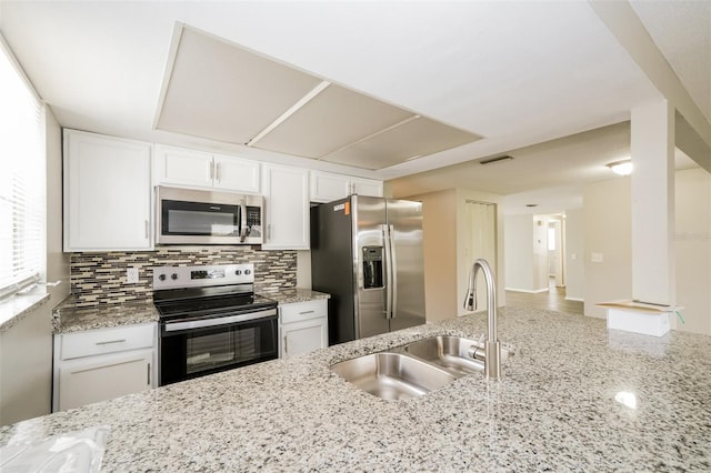 kitchen featuring white cabinetry, tasteful backsplash, light stone countertops, stainless steel appliances, and sink