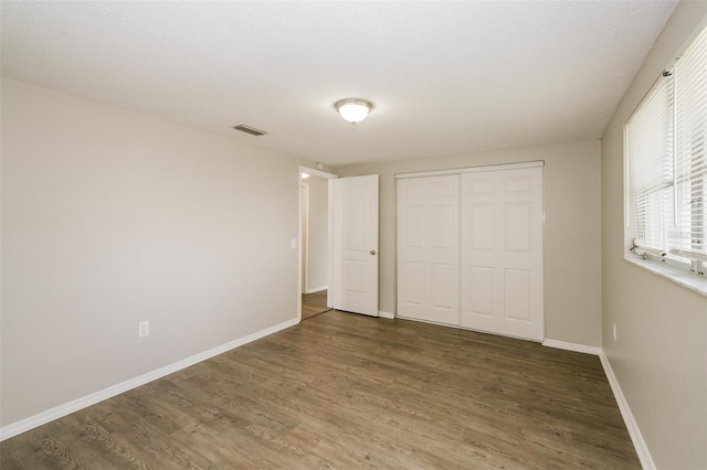 unfurnished bedroom with dark hardwood / wood-style floors and a closet