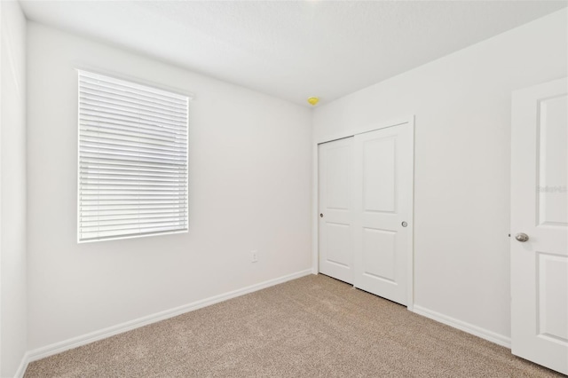 unfurnished bedroom featuring light carpet and a closet