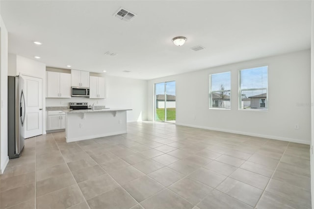 kitchen featuring visible vents, a breakfast bar, open floor plan, stainless steel appliances, and light tile patterned floors