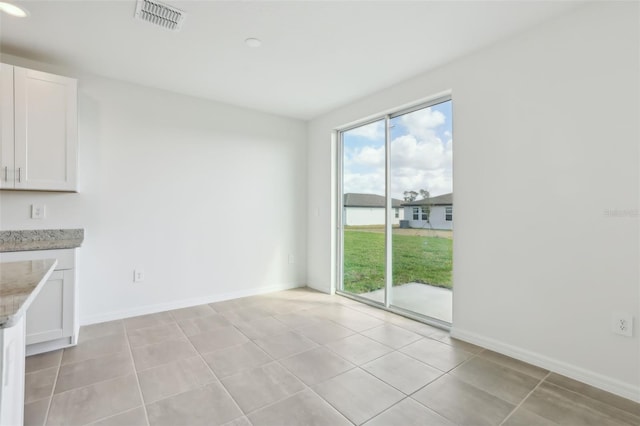 unfurnished dining area featuring light tile patterned floors, visible vents, and baseboards