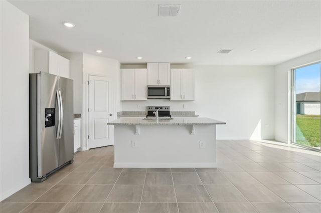 kitchen with light tile patterned flooring, white cabinets, stainless steel appliances, and a sink