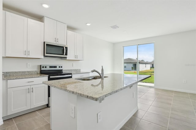 kitchen with a sink, light stone countertops, appliances with stainless steel finishes, and white cabinetry