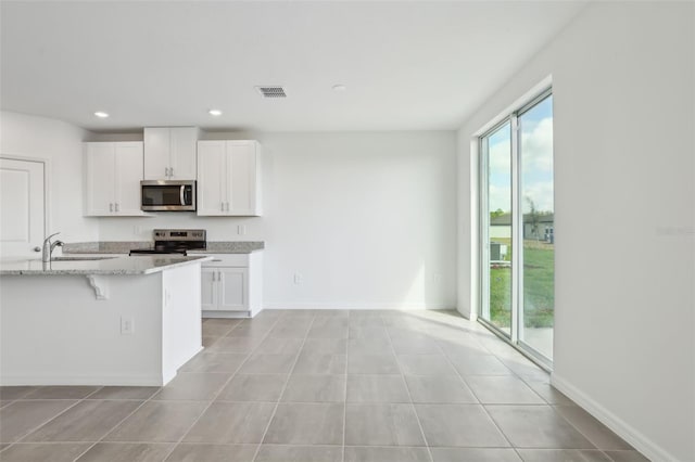 kitchen with light stone counters, visible vents, recessed lighting, appliances with stainless steel finishes, and white cabinetry