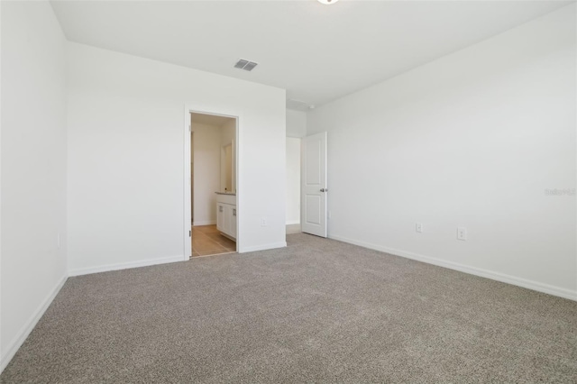 unfurnished bedroom featuring light carpet, visible vents, ensuite bathroom, and baseboards