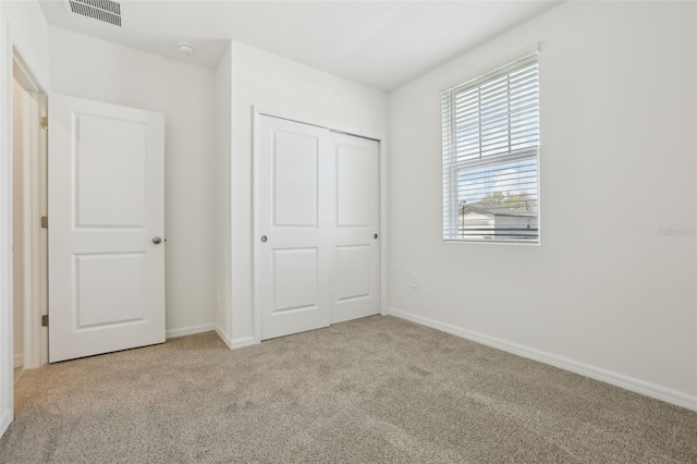 unfurnished bedroom with carpet flooring, baseboards, visible vents, and a closet