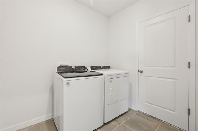 clothes washing area featuring washer and clothes dryer, laundry area, baseboards, and light tile patterned flooring